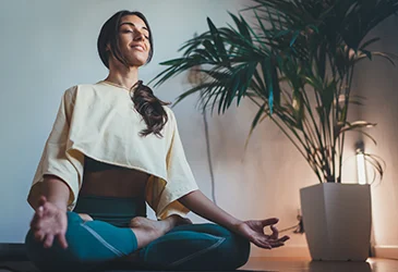 Woman sitting down meditating indoors